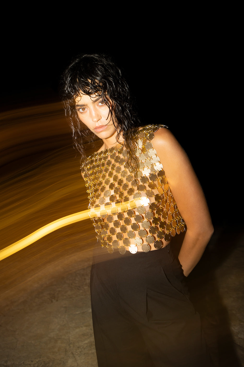 intricate metallic chain fabric on the gold boat neck top, showcasing its sculptural design.