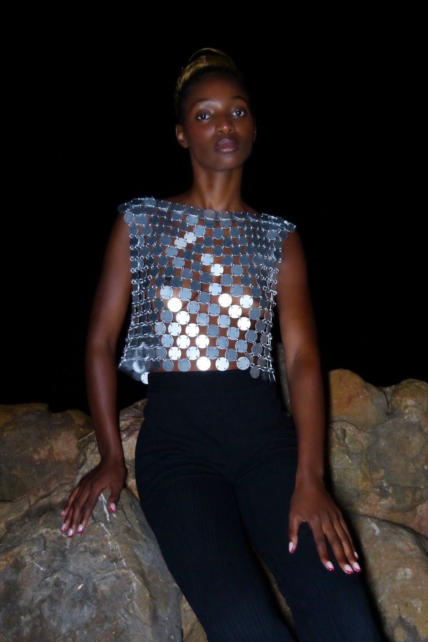 silver boat neck top, showcasing its shimmering chainmail texture and sculptural silhouette
